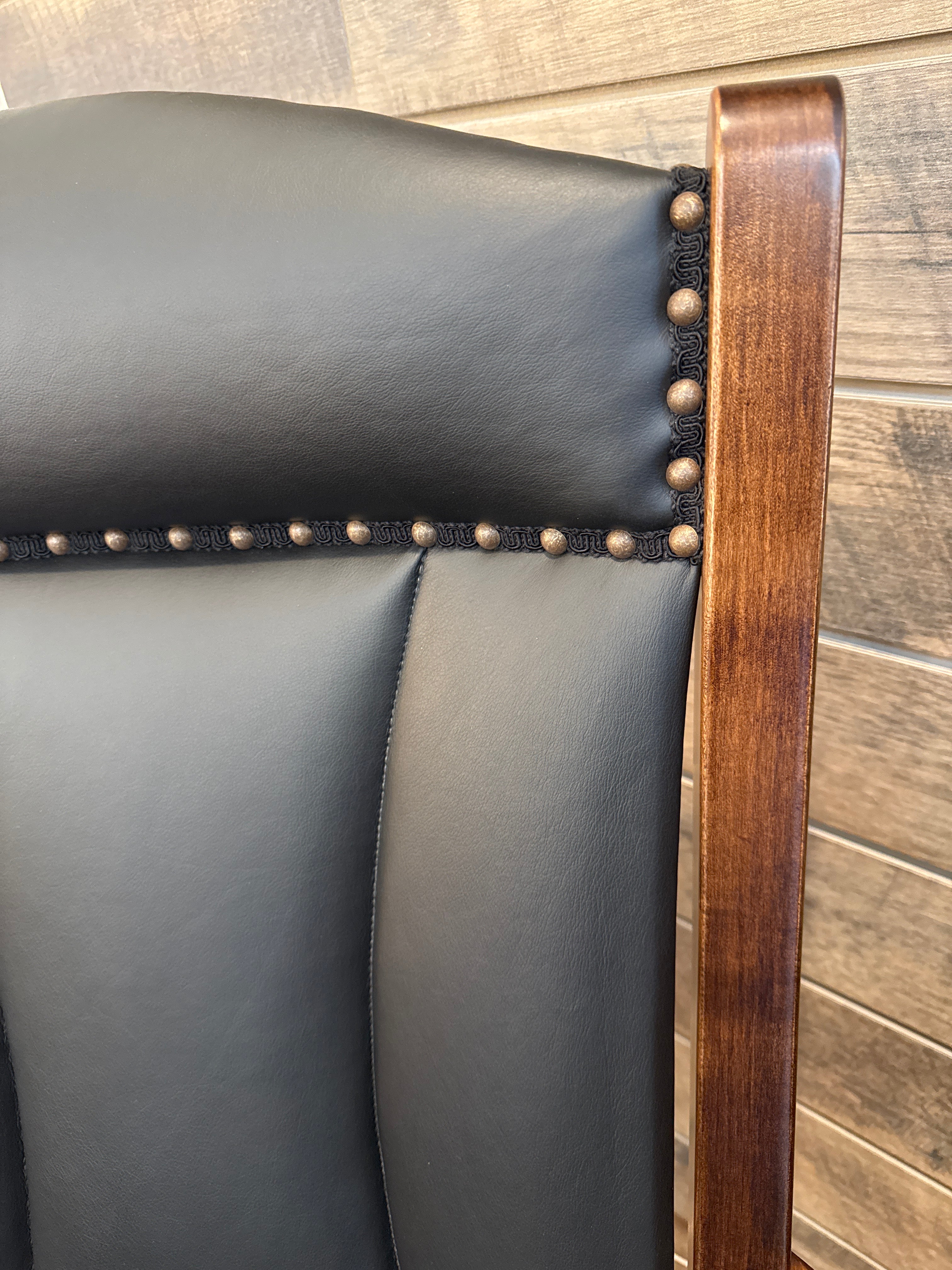 Close up view of corner detail on Amish made swivel glider rocker chair in solid maple hardwood with black leather upholstered cushions – handcrafted furniture